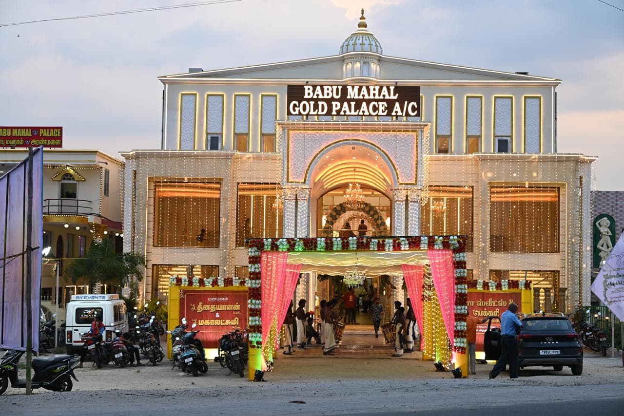 Fully illuminated palace facade at dusk with a pink-curtained entrance canopy and traditional drummers